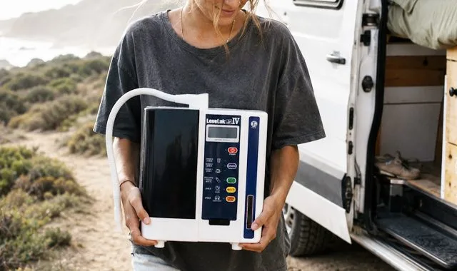 Cestovatel drží kompaktní LeveLuk JR IV vedle karavanu na pobřeží
